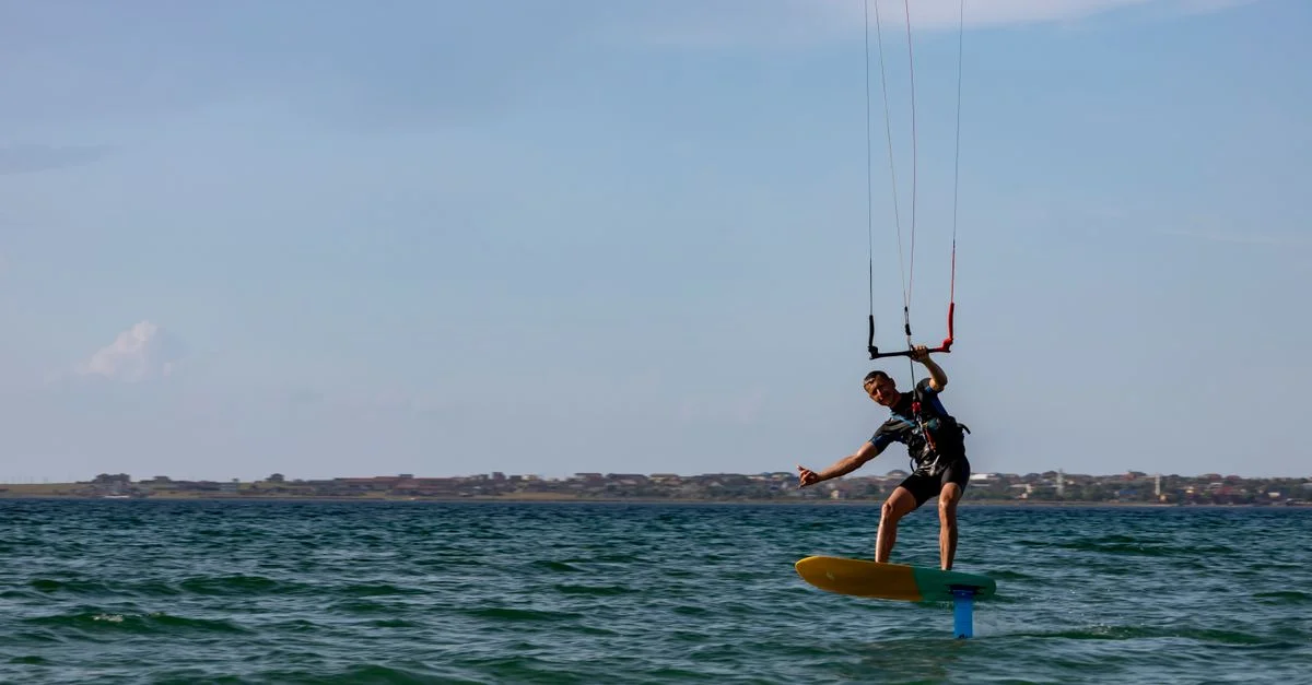 Image dynamique d'un kitesurfer glissant sur les eaux ouvertes de la mer, mettant en avant l'adrénaline et l'habileté.