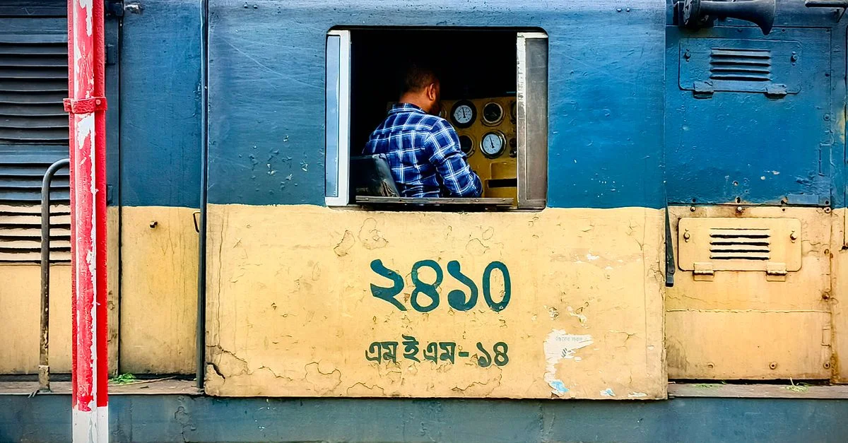 Un conducteur conduisant un train, se concentrant sur le panneau de commande à l'intérieur de la cabine de la locomotive.