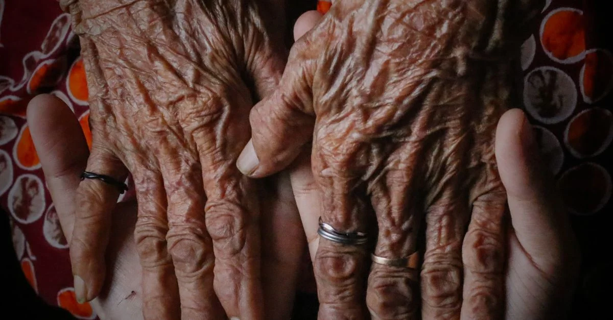 Une image en gros plan de mains âgées tenues par des mains plus jeunes, montrant l'âge et le soin.