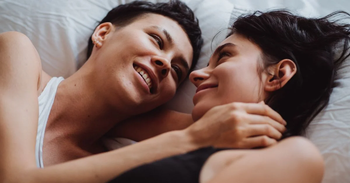 Un couple amoureux partageant un moment tendre au lit, s'étreignant et se souriant.