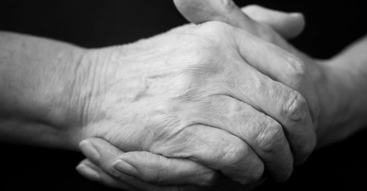 Gros plan de mains de personnes âgées jointes, symbolisant le soutien et l'attention.