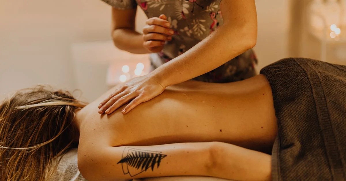 Femme recevant un massage relaxant du dos dans un cadre spa confortable, améliorant le bien-être et la détente.