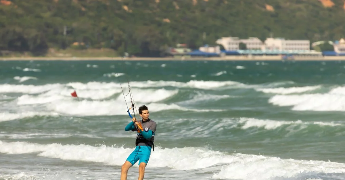 Homme faisant du kitesurf dans un océan ensoleillé avec des vagues, capturant l'aventure et le frisson des sports nautiques.