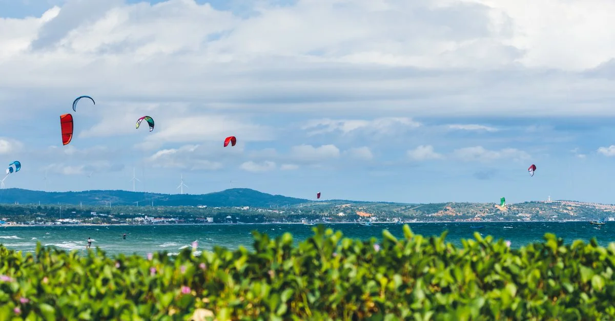 Des kitesurfers colorés profitent d'une journée palpitante en mer avec des vues pittoresques et une verdure luxuriante.