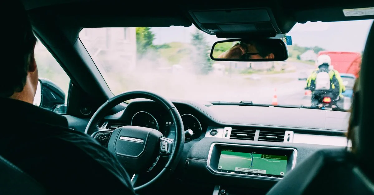 Vue intérieure d'une voiture avec navigation GPS et circulation à l'avant, mettant en valeur le transport urbain.