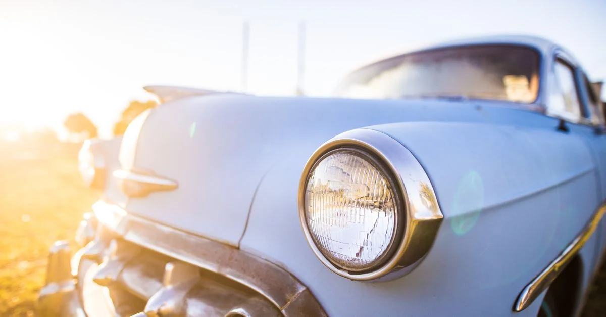 Un gros plan vibrant du phare d'une voiture vintage avec un flaire solaire mettant en valeur son design classique.