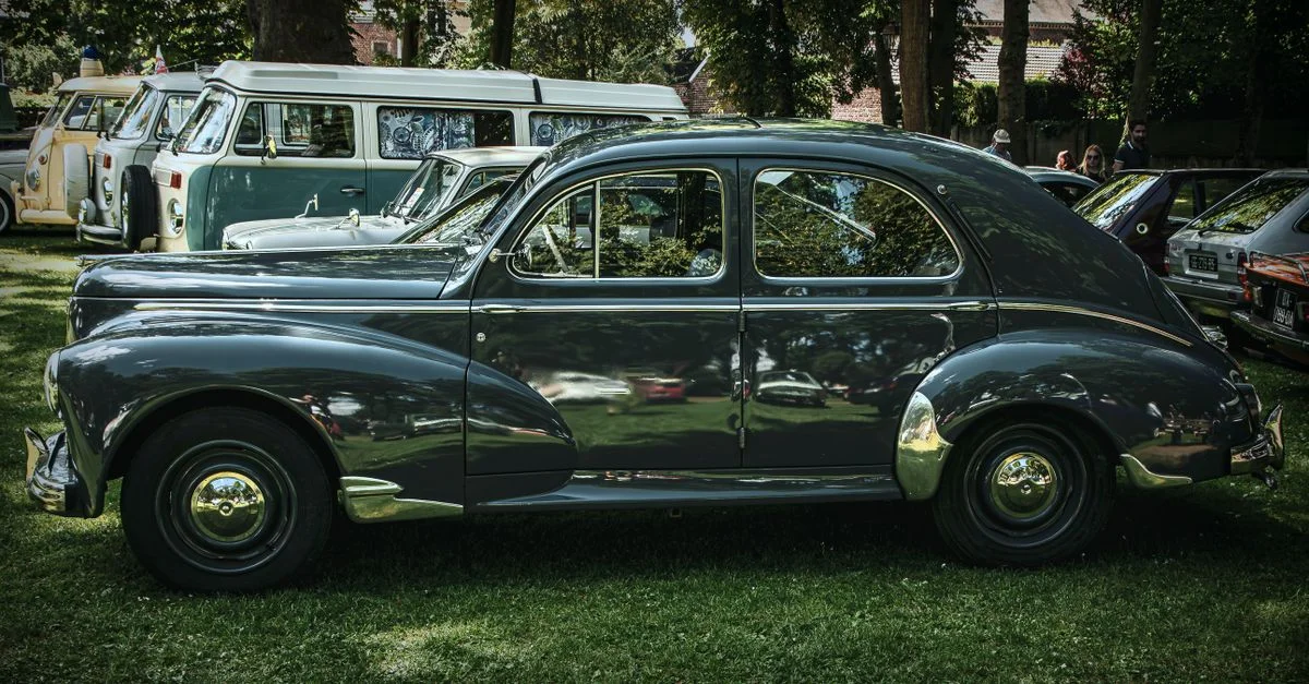 Voiture vintage exposée lors d'une exposition automobile en plein air parmi des véhicules classiques.